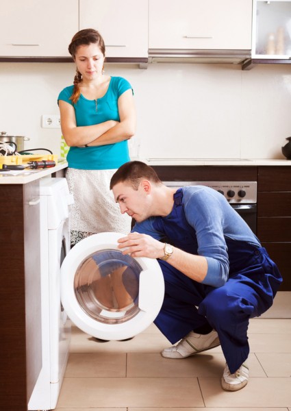 Woman  watching as worker repairing washing machine